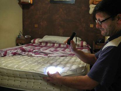 Un vecino de Lavapiés inspecciona su colchón en busca de chinches.