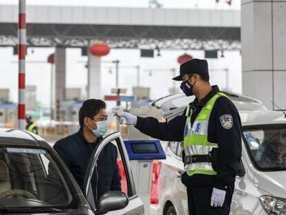 Un funcionario de policía toma la temperatura a un conductor en Wuhan.