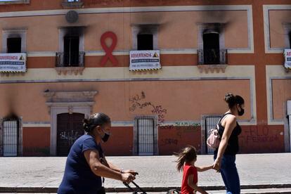 Tres mujeres caminan frente al Palacio Municipal de Fresnillo, Zacatecas, quemado tras una protesta por el feminicidio de una menor.