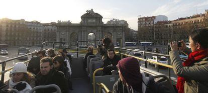 Un grupo de visitantes en un autobús turístico en Madrid, a su paso por la Puerta de Alcalá.