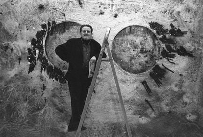 El pintor Juan Genovés, subido a una escalera, delante de una de sus obras en la galería Malborough de Madrid, en 1995. 