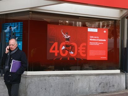Un hombre habla por teléfono delante de una sucursal del Banco Santander, en Madrid.