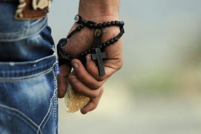 Un palestino, con un rosario y una piedra, se enfrenta a las tropas israelíes en Bir Zeit, Ramala, durante una protesta por los bombardeos sobre Gaza.