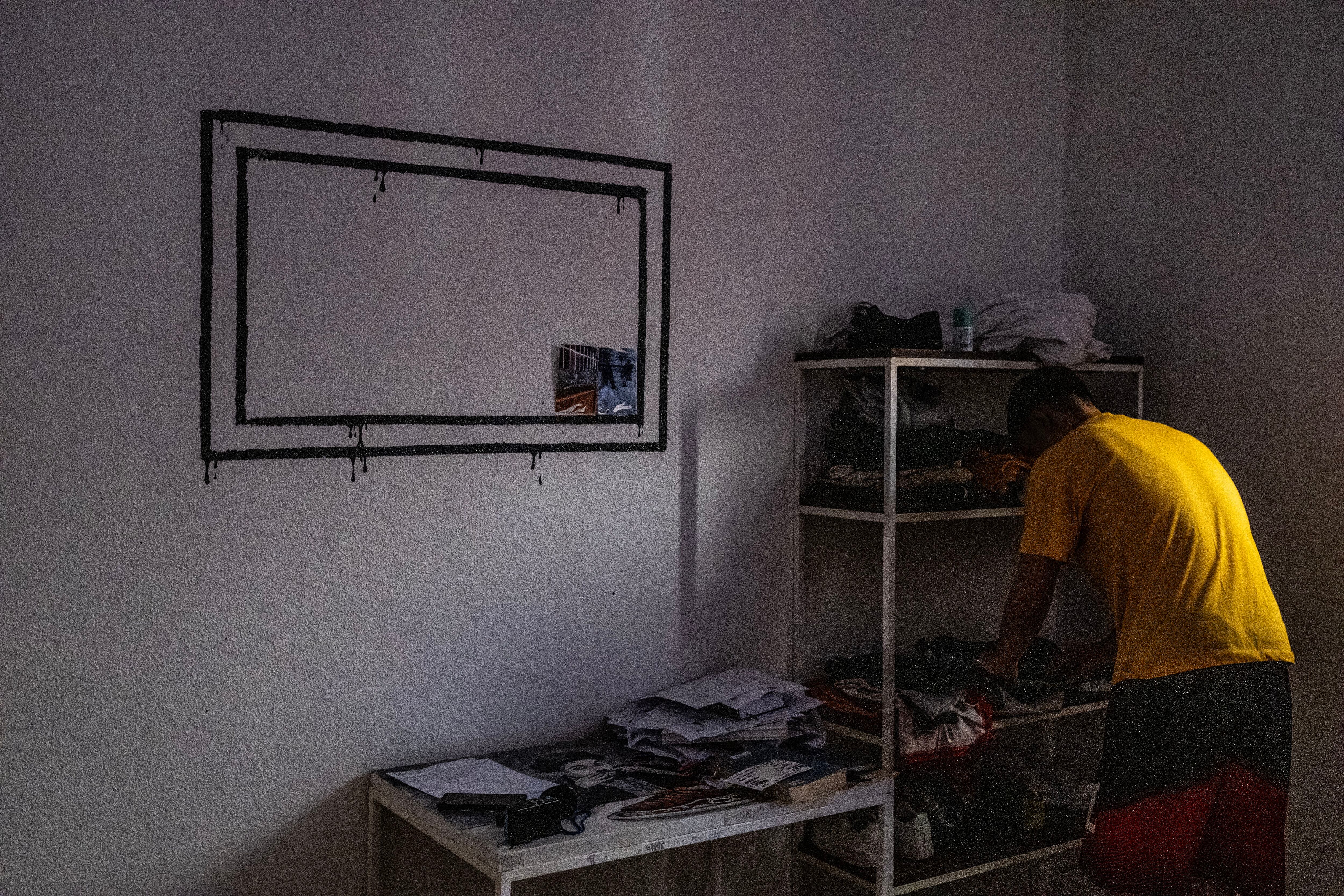 Pablo, en su habitación del centro de menores, ordena algunas camisteas en la estantería.