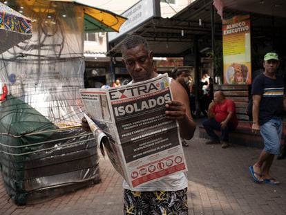 Un hombre lee un periódico con el titular en portugués "Aislado. Río en guerra contra el coronavirus" en Río de Janeiro, Brasil, el 20 de marzo de 2020.