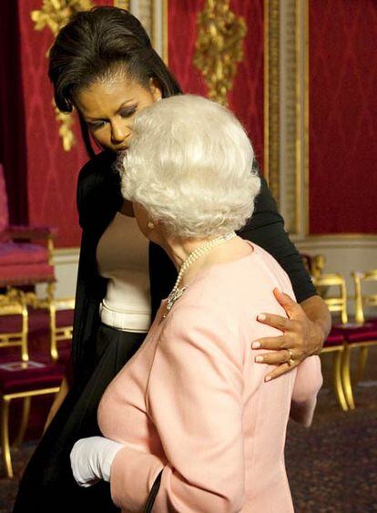 La reina Isabel y Michelle Obama, abrazadas, en un salón de palacio.