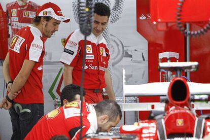 Alonso observa el trabajo de los mecánicos de Ferrari en los talleres del circuito de Interlagos.