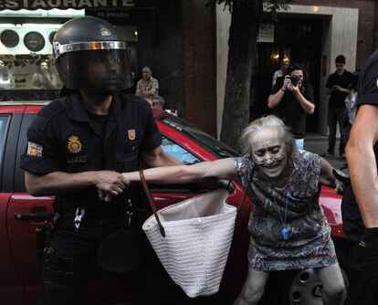 Un agente antidisturbios agarra del brazo a una mujer en Madrid durante las protestas contra los recortes.