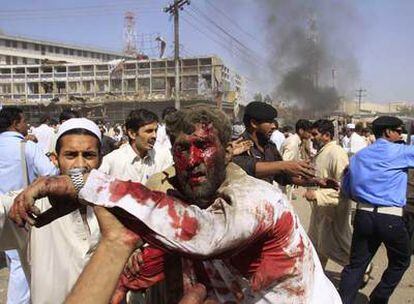 Policías y civiles ayudan a evacuar a los heridos del atentado suicida ocurrido ayer en la ciudad paquistaní de Peshawar.