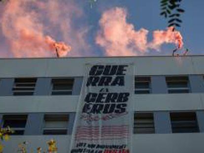 Algunas personas encienden botes de humo y despliegan una pancarta en el terrado del edificio de la sede de Haya Real State.