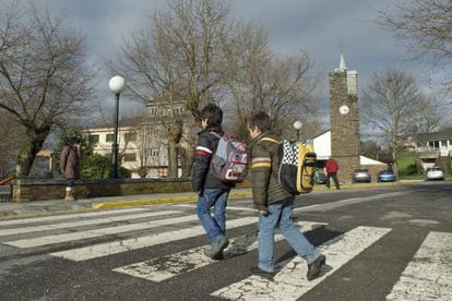 Dos escolares de O Incio cruzan un paso de peatones mochila al hombro