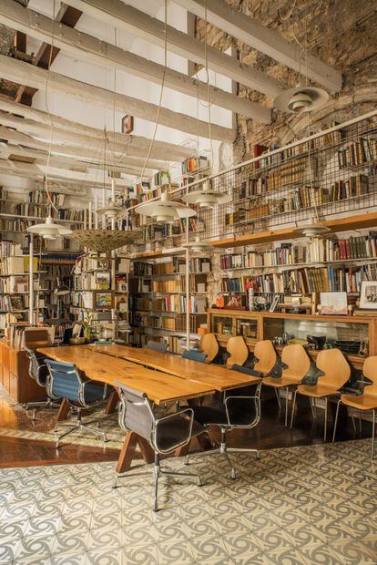 Las mesas de madera de la biblioteca están hechas con troncos de árboles. La doble altura de esta estancia se logró renunciando al piso superior y dejando las antiguas vigas vistas.
