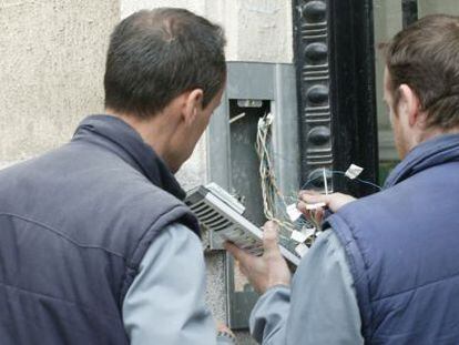 Unos electricistas reparan un portero autom&aacute;tico. 
