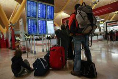 Varios pasajeros consultan los horarios de embarque en la terminal 4 de Barajas.