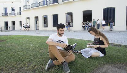 Dos estudiantes leen en uno de los jardines de la Facultad de Derecho de la Universidad de Sevilla.