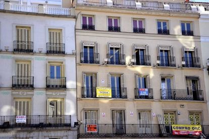 Fachada de un edificio de Madrid con diferentes carteles de venta y alquiler de pisos.