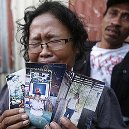 Una mujer llorosa muestra fotos de familiares que iban a bordo del ferry que naufragó en aguas de Indonesia