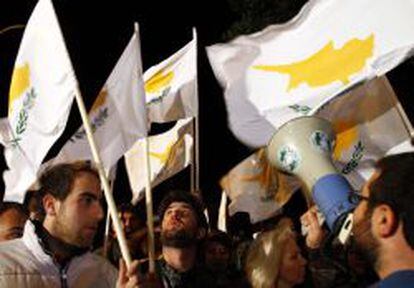 Varios asistentes muestran pancartas durante una manifestaci&oacute;n frente al Parlamento de Chipre.