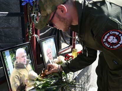 Un miembro del grupo mercenario privado Wagner rinde homenaje a Prigozhin (foto de la izquierda) y Utkin, frente a una oficina de Wagner, este jueves en Novosibirsk.