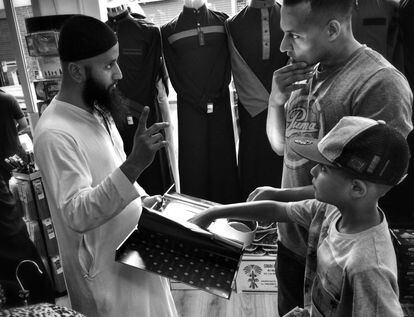 Un hombre con su hijo en un atienda de ropa junto a la mezquita.