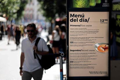 Un viandante camina junto a un cartel donde un restaurante anuncia un menú del día, en Madrid, la semana pasada.