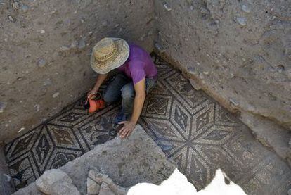 Un arqueólogo limpia el mosaico romano encontrado en Cástulo (Jaén).