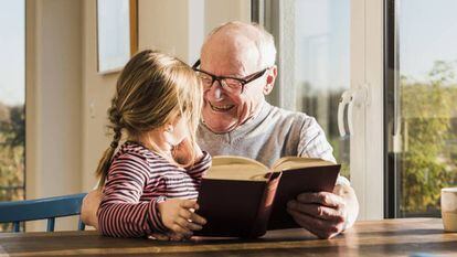 Un hombre lee un libro con su nieta.