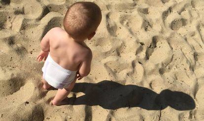 Un bebé juega en la playa.