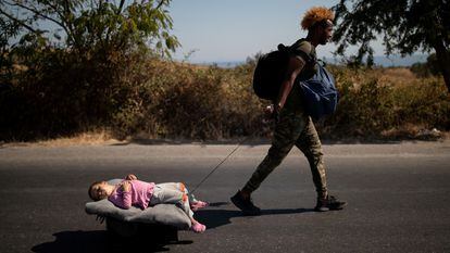 Un migrante arrastra a un bebé por una carretera en Lesbos (Grecia).