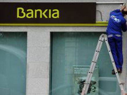 Un trabajador instala el logotipo de Bankia en una de las oficinas de la entidad.