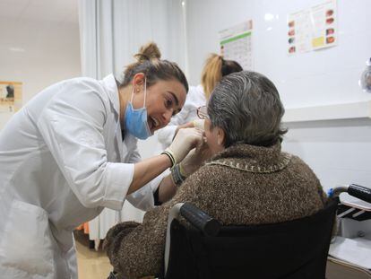 Una dentista examina la dentadura de una persona mayor.