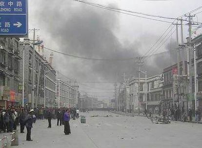 Una calle de Lhasa, tras los disturbios el viernes pasado, llena de humo de las tiendas quemadas y bicicletas volcadas.