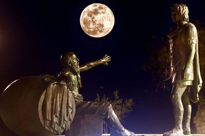 La 'superluna de nieve' se alza entre las estatuas de Alejandro Magno (a la derecha) y Diógenes de Sínope, en Corinto (Grecia).