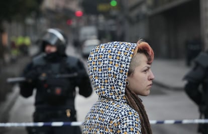 La policía ha desalojado a 103 personas (93 del hotel Madrid y 10 del inmueble del Albéniz). Diez de ellos fueron detenidos, nueve por encontrarse en situación irregular en España y uno por cultivo de marihuana. En la imagen, una joven observa el desalojo desde la barrera policial.