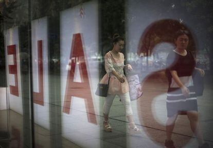 Una mujera pasa antes unos almacenes en rebajas, en Pekín.