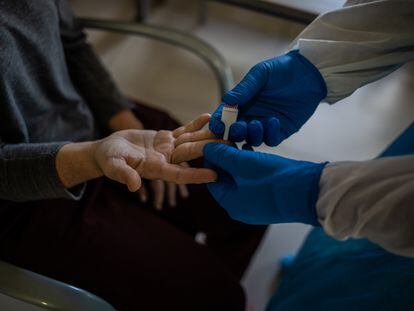 Un voluntario de la ONG Proactiva Open Arms realiza un test rápido de Covid-19 extrayendo sangre en una residencia geriátrica de Sant Pere de Ribes, Barcelona.