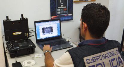 Fotografía facilitada por la Policía Nacional de un agente que analiza material informático de la operación.