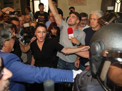 La exdiputada de Andalucía Macarena Olona (en el centro de la imagen) intenta acceder al paraninfo de la Facultad de Derecho de Granada este jueves, rodeada de manifestantes y de agentes antidisturbios.