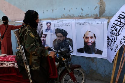 A militiaman looks at posters of Taliban leaders Haibatullah Akhundzada (right) and Abdulghani Baradar, in Kabul, on Aug.25, 2021.