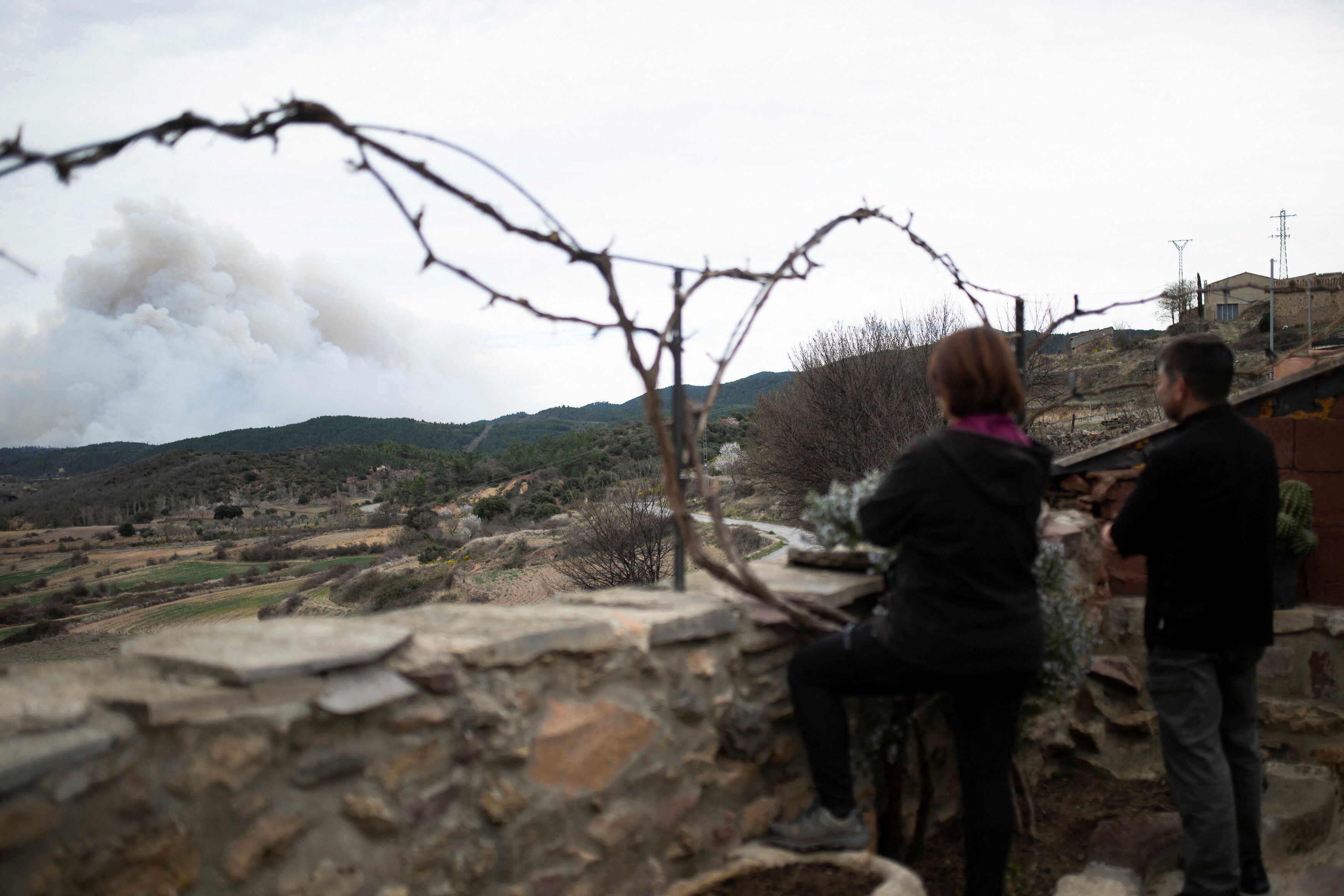 Dos personas observaban el jueves el humo del incendio en el municipio de San Agustín, en Teruel.