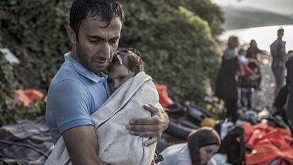 Un hombre abraza y seca a su hijo momentos después de desembarcar en la costa norte de la isla Lesbos tras cruzar el Mar Egeo en un una barca de plástico.