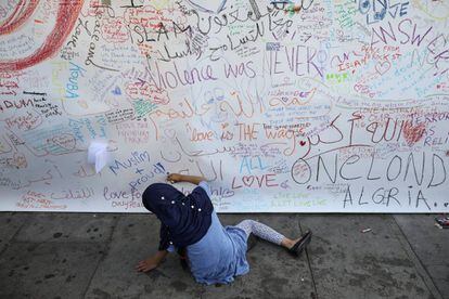 Una niña escribe una dedicatoria en el muro junto a la mezquita.