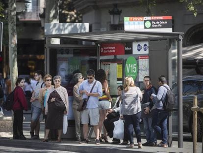 Ciutadans i turistes esperen en una de les parades del passeig de Gràcia per on passen busos que van al Park Güell.