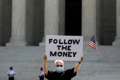 Un manifestante alza una pancarta con la leyenda "Seguid el dinero" ante el Tribunal Supremo de EE UU, en Washington, el 9 de julio de 2020.