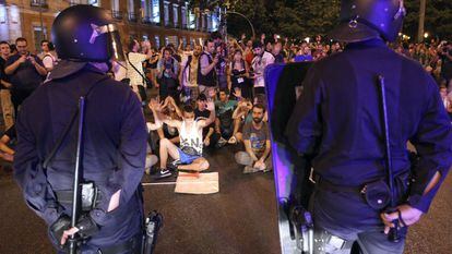 Participantes en las protestas de Madrid ocupan una calle ante un cordón policial tras choques entre agentes y manifestantes.