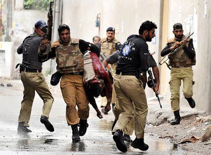 Agentes de la policía pakistaní llevan a uno de los fieles heridos en los asaltos a dos mezquitas en Lahore.
