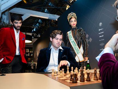 Carlsen (sentado), Gukesh (de pie) y Aronián analizan este viernes una posición inicial junto a Miss Angola, invitada especial para la inauguración del torneo