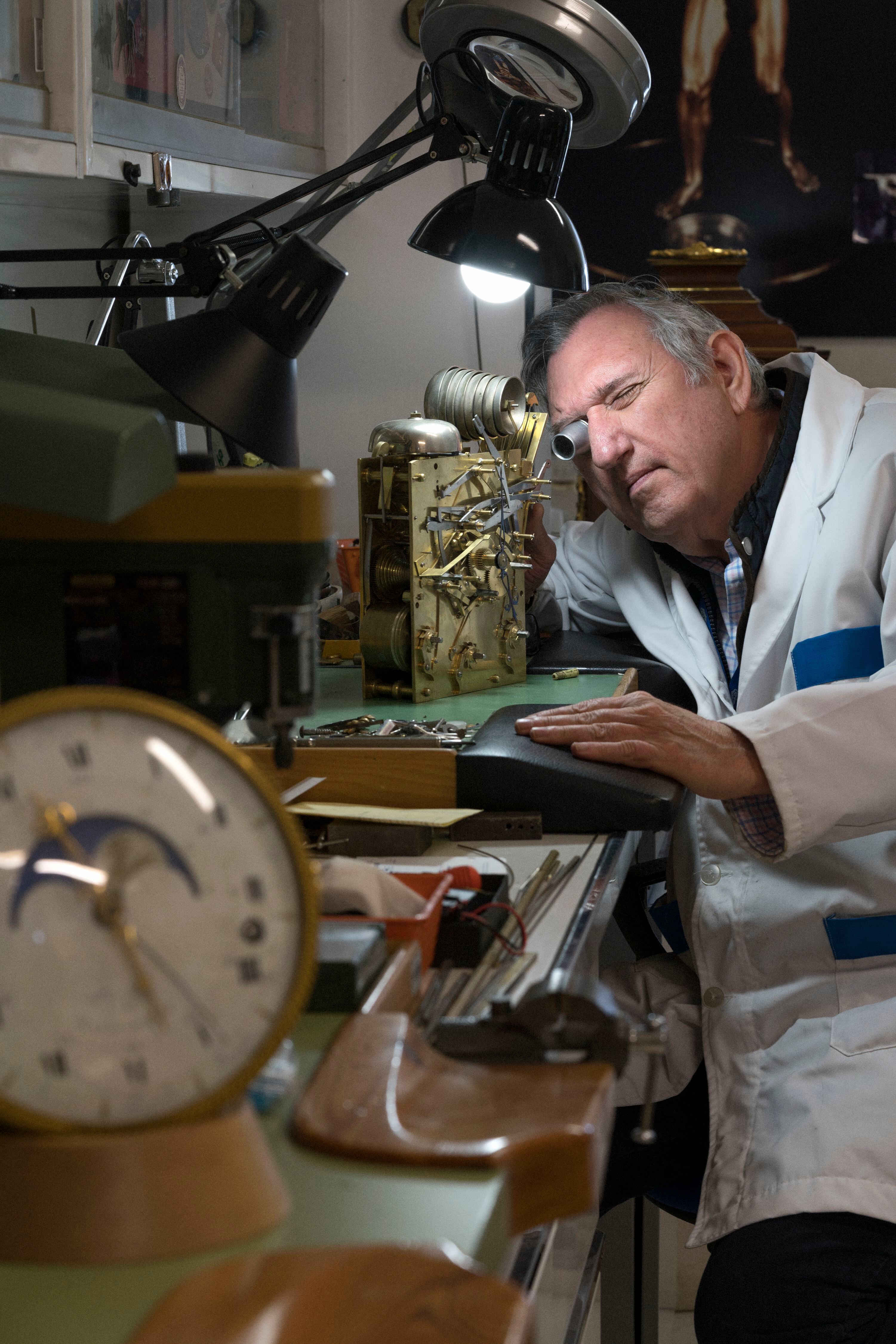 El encargado del taller de relojería, Manuel Santolaya, observa la maquinaria de un reloj 'bracket' inglés del siglo XVIII.