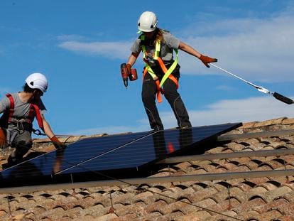 Dos operarios instalan placas solares en una vivienda.