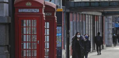 Varias personas andan por las calles vacías de Londres, que tiene cerrados los establecimientos por la pandemia.